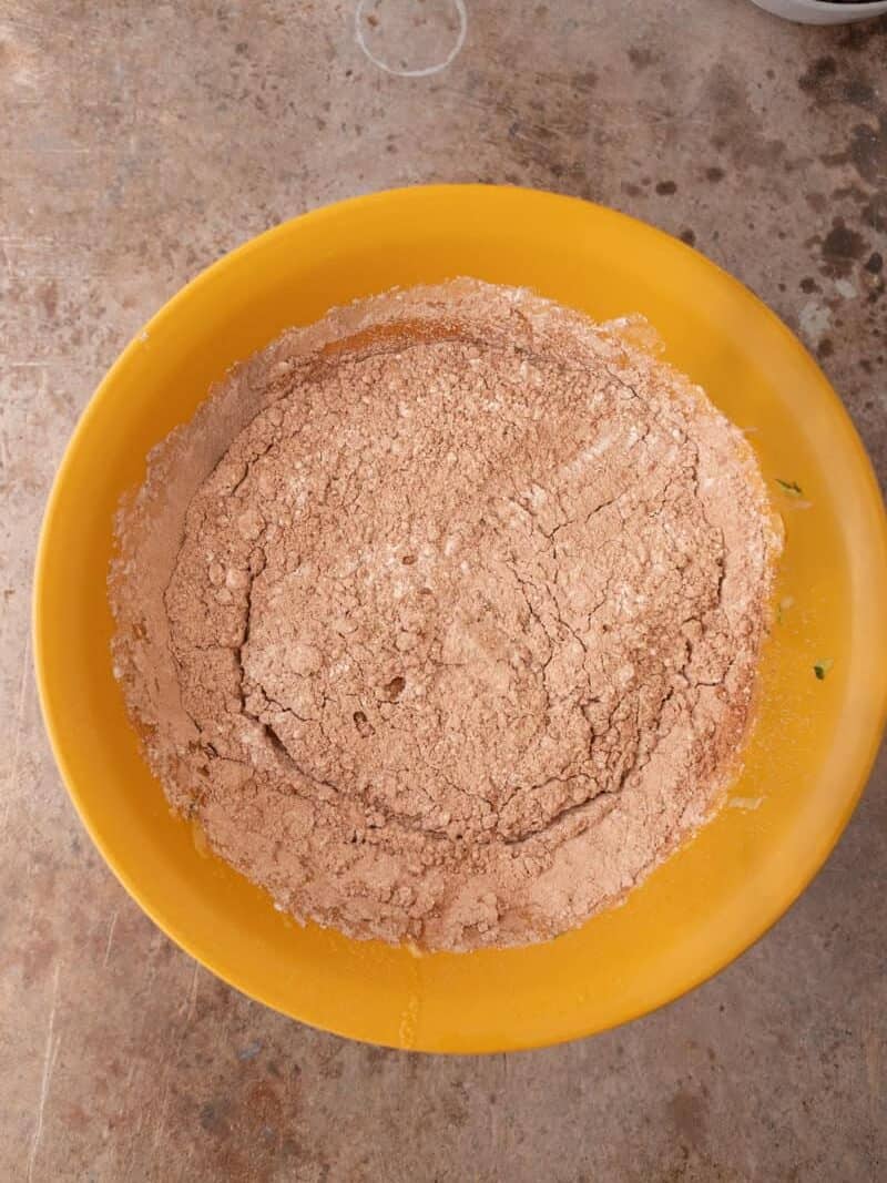 Dry ingredients in a yellow bowl including flour and cocoa powder