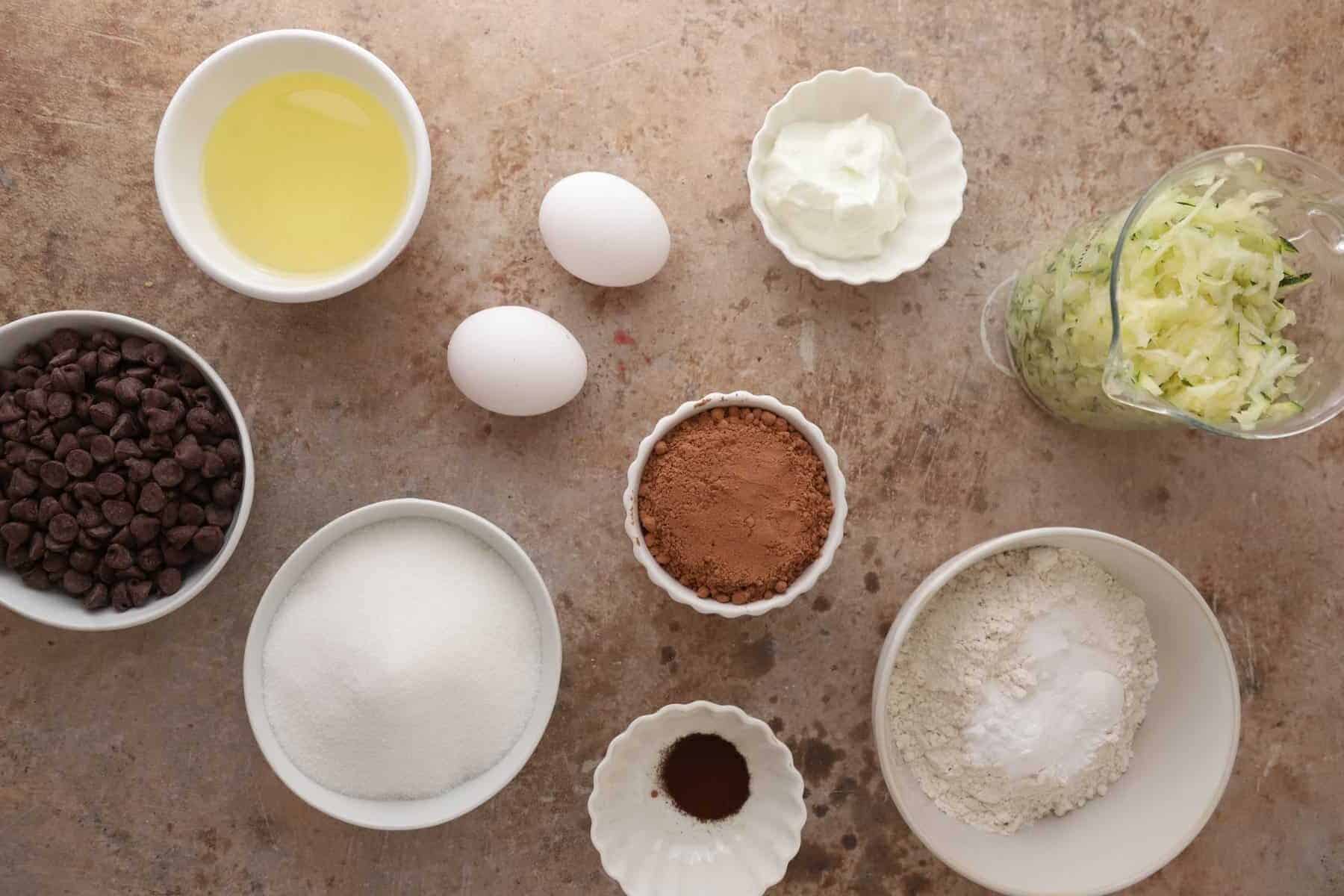 Ingredients on the counter including cocoa powder chocolate chips and shredded zucchini