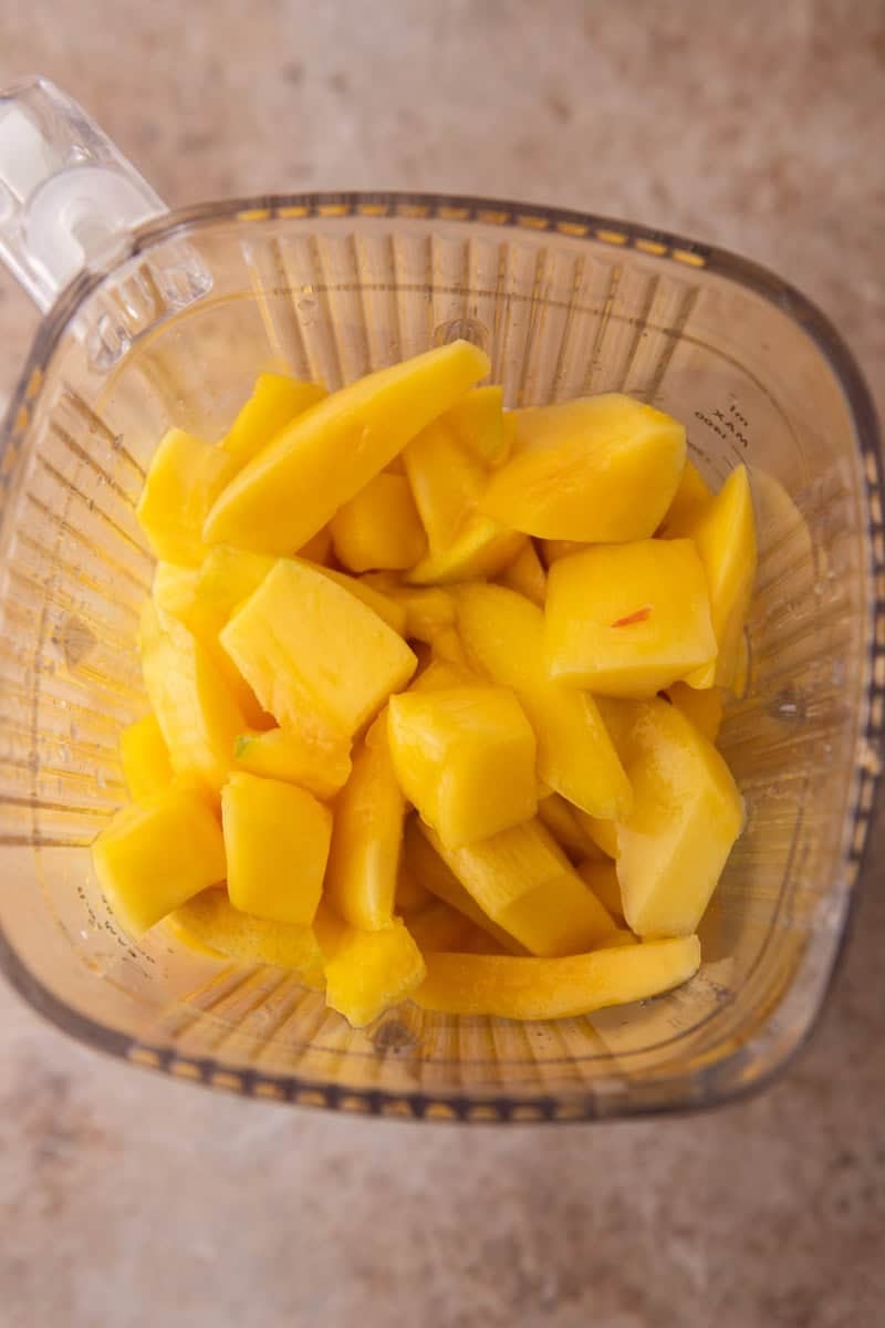 Fresh mango chunks in a blender before blending smoothly