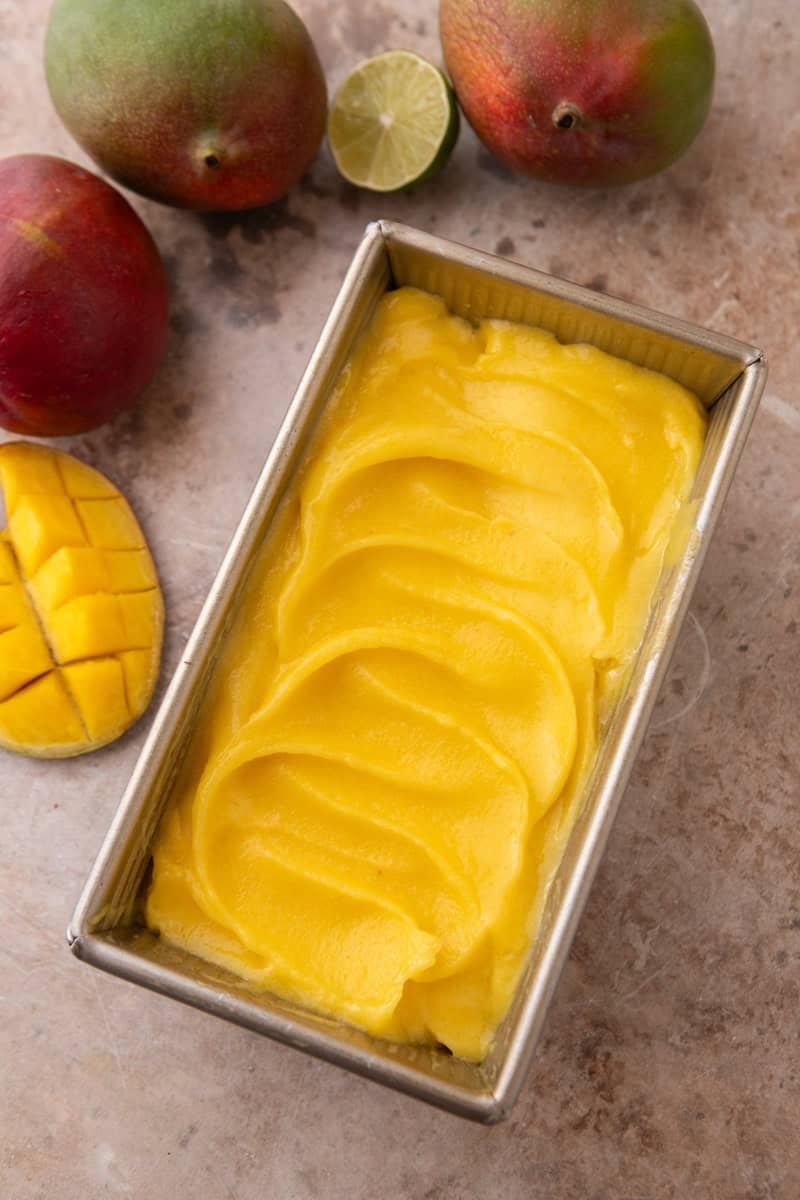 Freshly churned mango sorbet swirled into a metal loaf pan