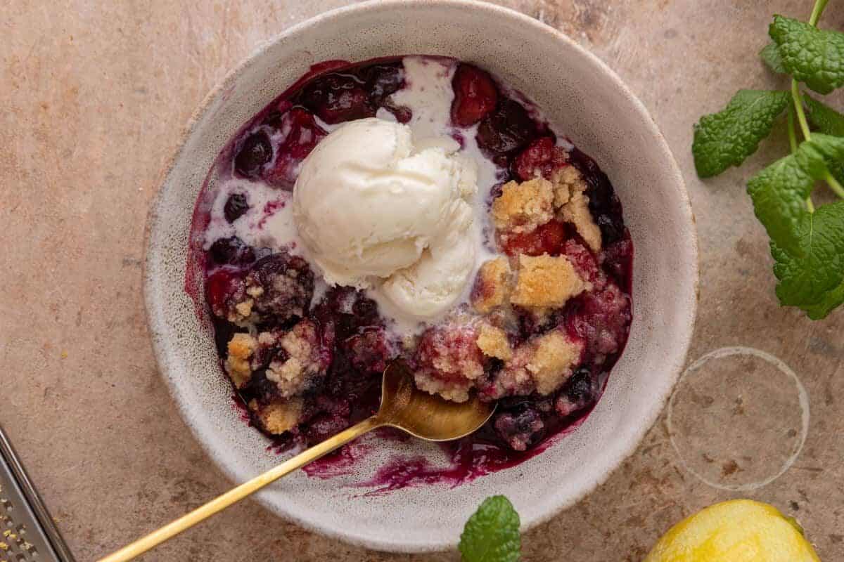 Serving of mixed berry cobbler with streusel topping in a bowl