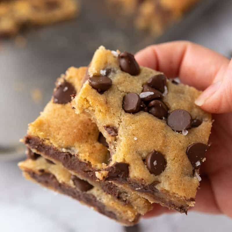 Hand holding a thick soft Nestle Toll House cookie bar showing chewy texture