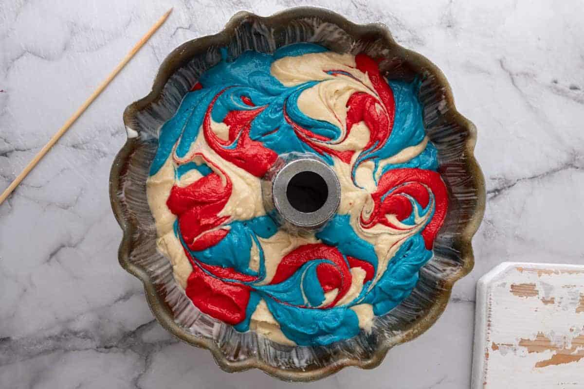 Red, white, and blue 4th of July bundt cake batter swirled in a bundt pan.