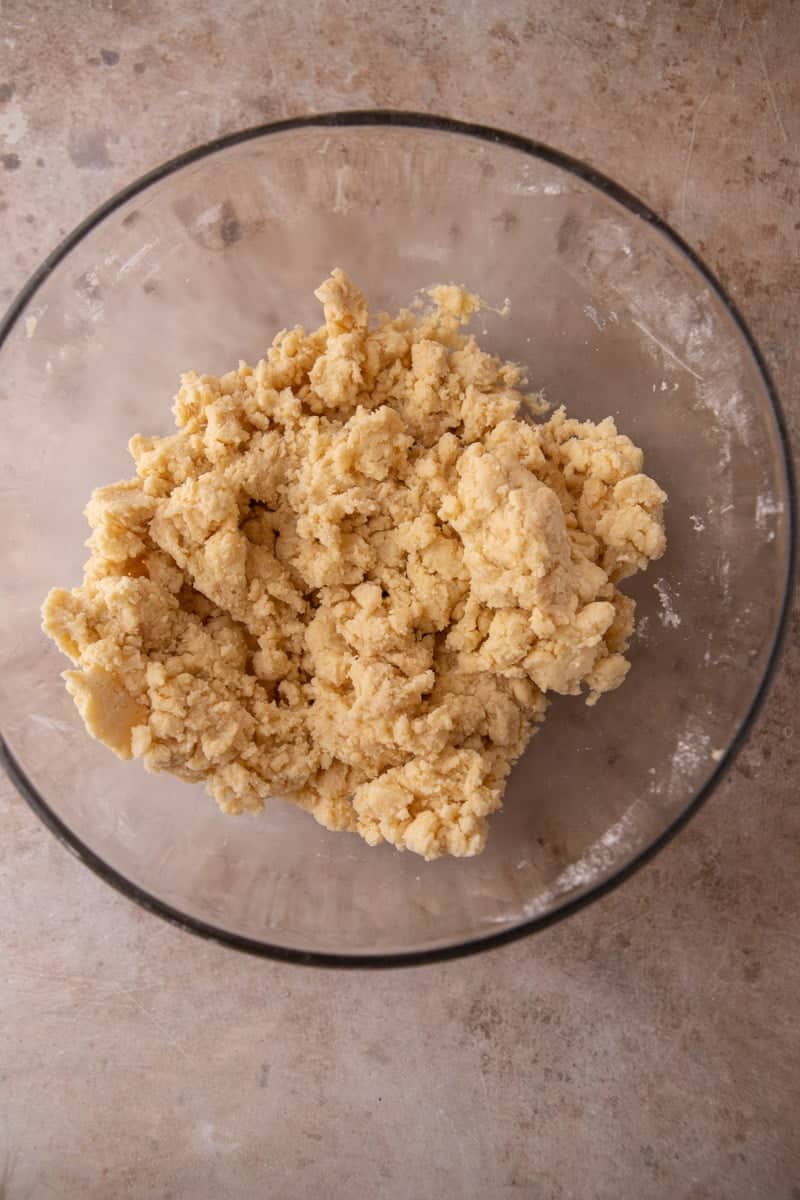 Shortbread crumble dough mixed to a coarse shaggy texture in a glass bowl, ready to press into the pan