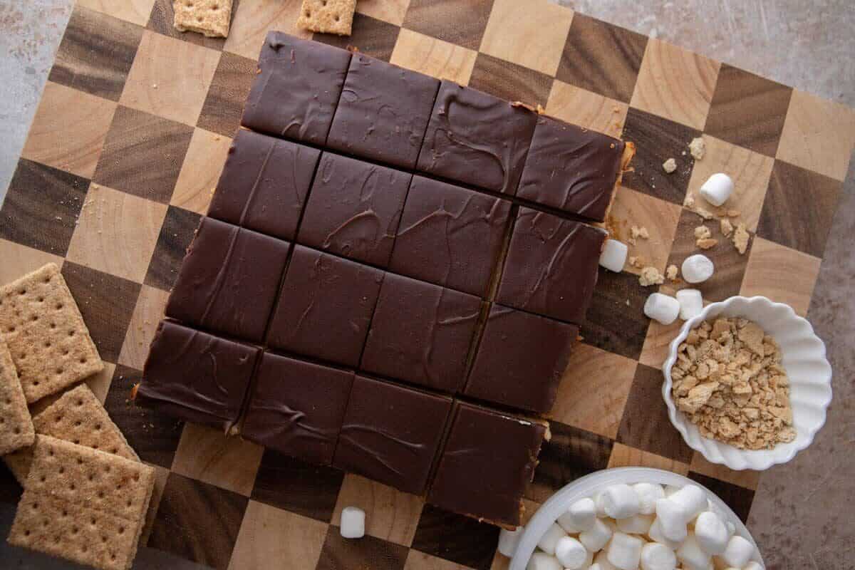 Sixteen s'mores cheesecake bar squares cut with a chocolate ganache top, ready for the toasted marshmallow topping