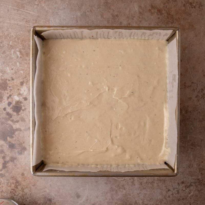 Marshmallow cheesecake batter poured smooth into the prepared 8x8 pan for s'mores cheesecake bars