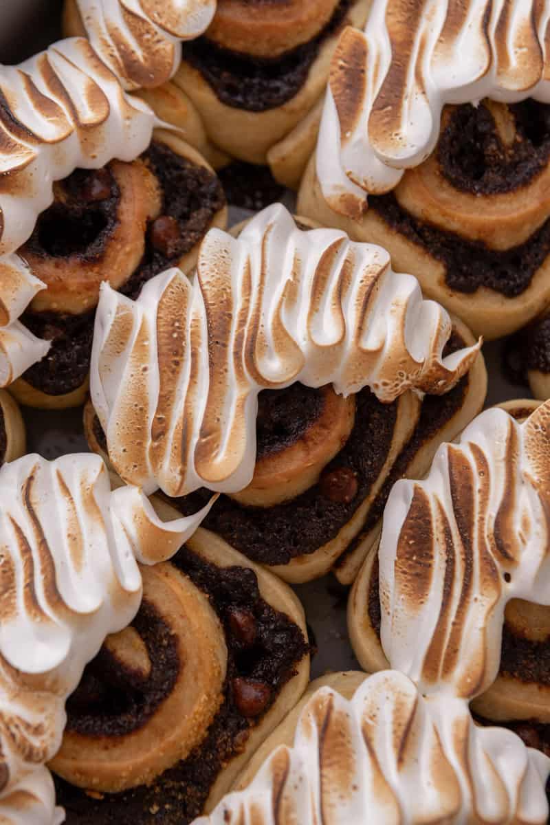 Close up of baked s'mores cinnamon rolls topped with torched golden Swiss meringue