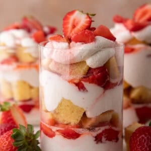 Strawberry shortcake cups showing distinct layers of cake, whipped cream, and sweet macerated strawberries.