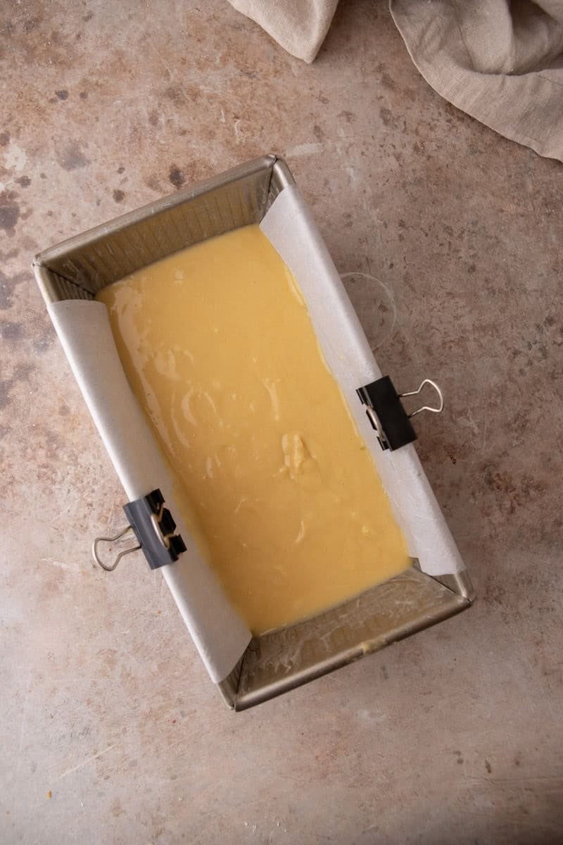Vanilla cake batter poured into a parchment lined loaf pan before baking