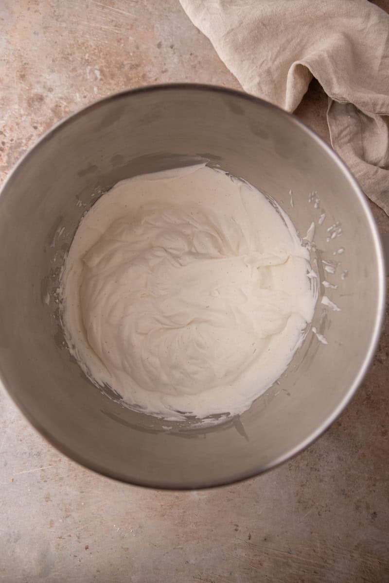 Vanilla bean whipped cream whipped to soft peaks in a stainless steel bowl