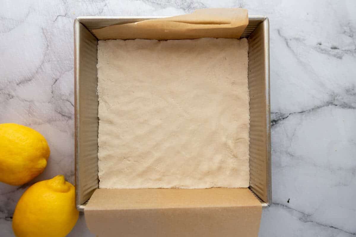 Shortbread crust pressed into a parchment-lined 8x8 inch pan