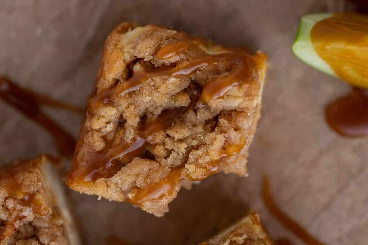 Sliced apple cheesecake bars showing shortbread crust, cheesecake, and oat streusel layers