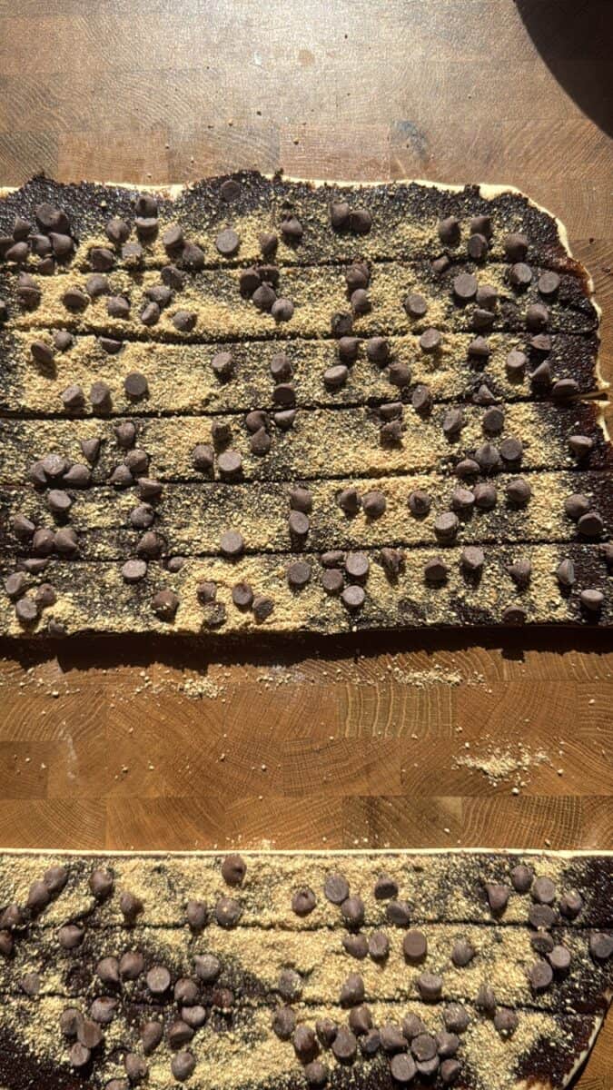 Chocolate and graham covered dough cut into strips for rolling into cinnamon rolls