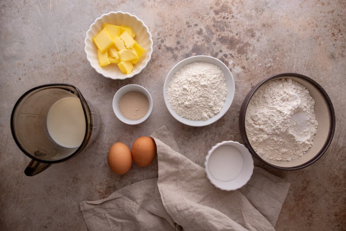 Ingredients for brioche cinnamon roll dough including flour, butter, eggs, and yeast