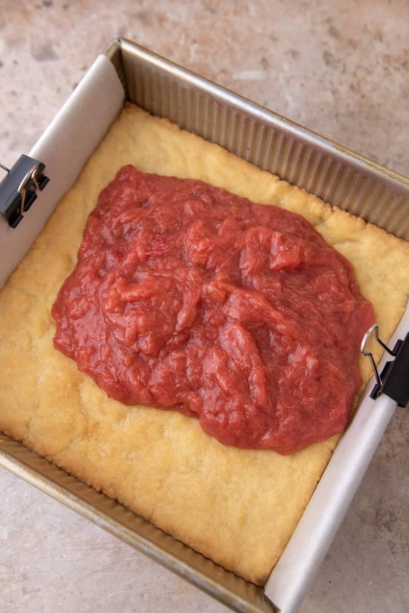 Jammy rhubarb filling spread over the par-baked shortbread crust in the 8x8 baking pan