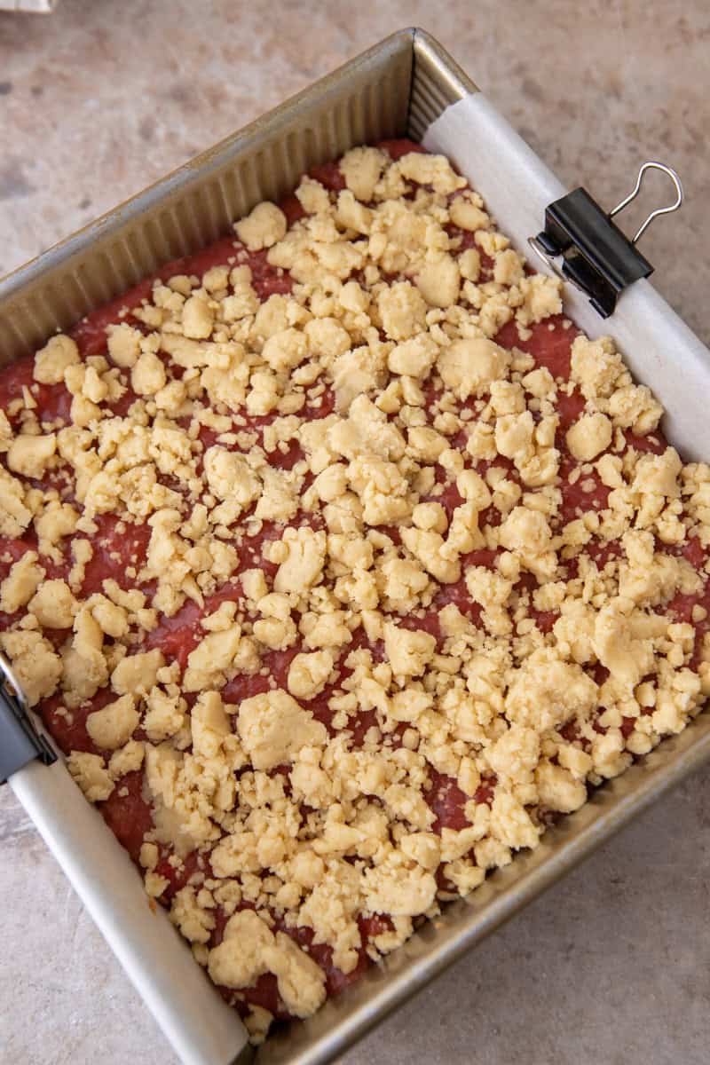 Shortbread crumble topping scattered over the rhubarb filling in the 8x8 baking pan, ready to bake