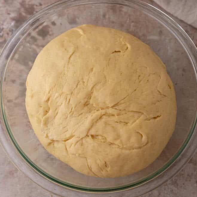 Brioche dough doubled in size in a glass bowl after the first rise