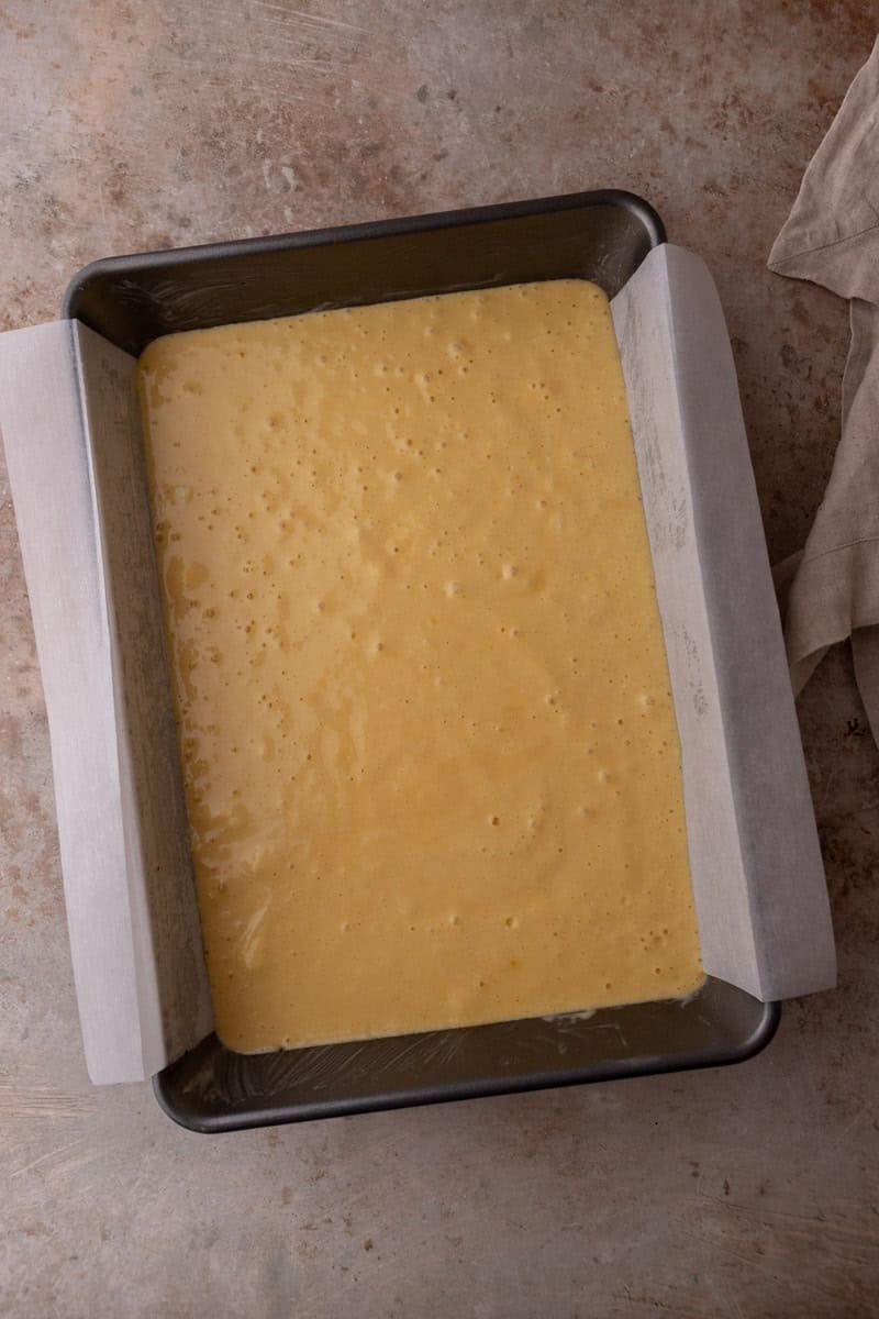 Tres leches cake batter poured into a parchment lined 9x13 pan
