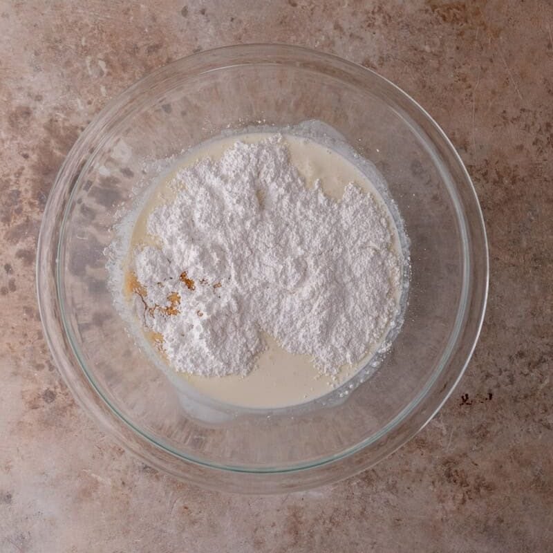 Heavy cream, powdered sugar, and vanilla in a bowl before whipping