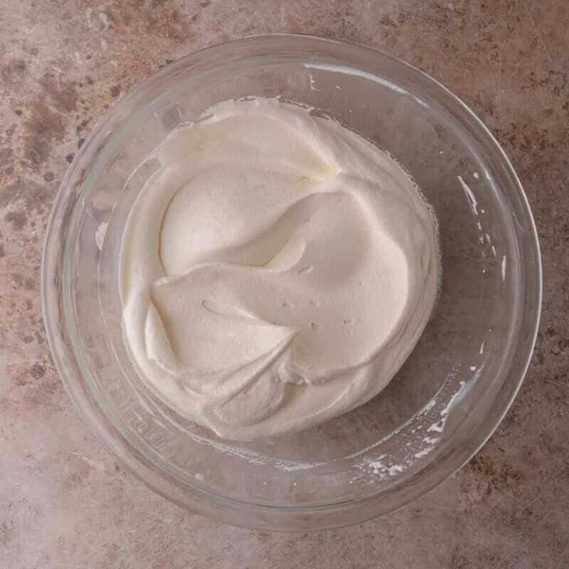 Softly whipped cream in a glass mixing bowl