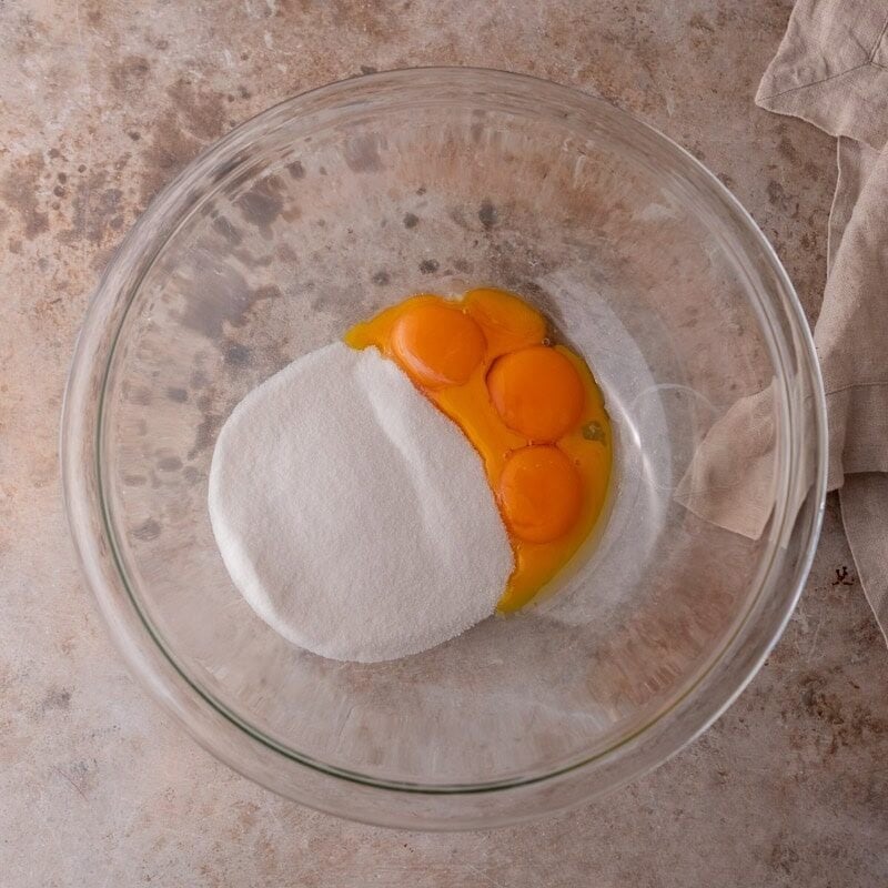 Egg yolks and sugar in a glass bowl before mixing for batter