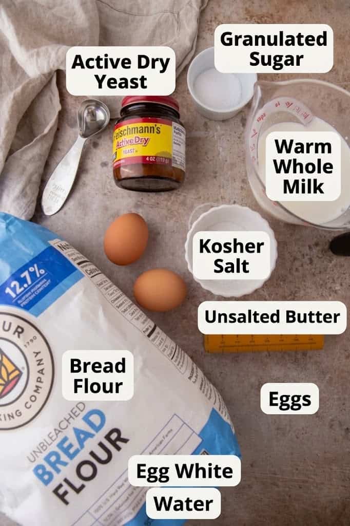 Ingredients for homemade hoagie rolls including yeast, milk, sugar, eggs, and bread flour laid out on the counter.