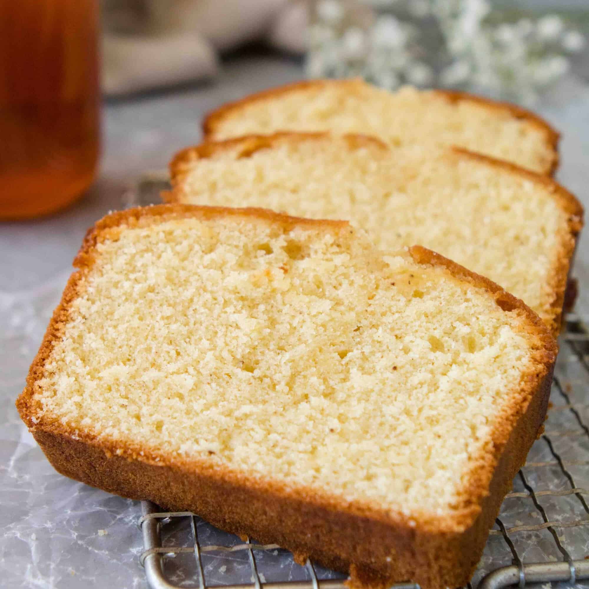 Honey tea cake slices arranged on a board beside a cup of tea and honey.