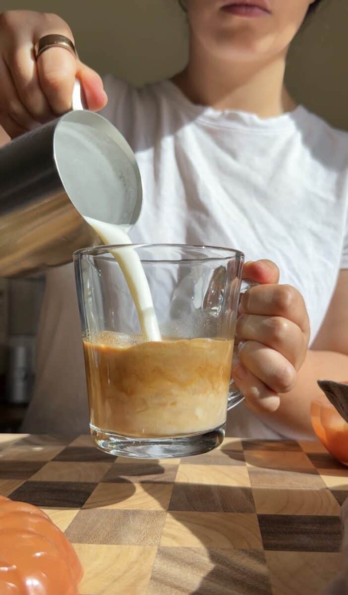 Steamed milk poured into a mug of pumpkin spiced espresso to build the latte.