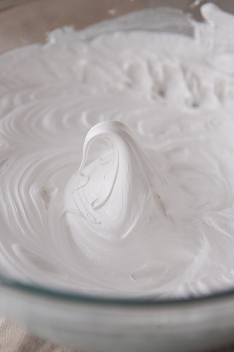 Stiff glossy meringue peak in a bowl, showing the meringue is ready to pipe.