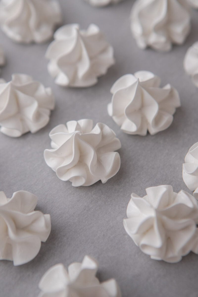 Rows of meringue swirls piped with a star tip onto parchment.