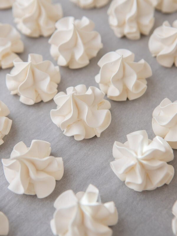 Baked crispy vanilla meringue cookies on a baking sheet.