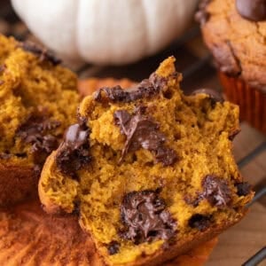 Pumpkin muffin broken in half showing melted chocolate pools through the soft orange crumb.