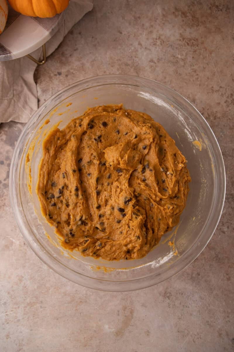 Chocolate chips folded evenly through the orange pumpkin muffin batter with a spatula.