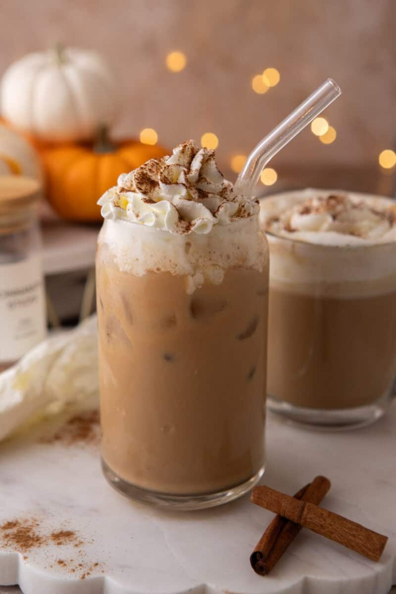 Iced pumpkin spice latte in a tall glass with cold milk poured over ice cubes.