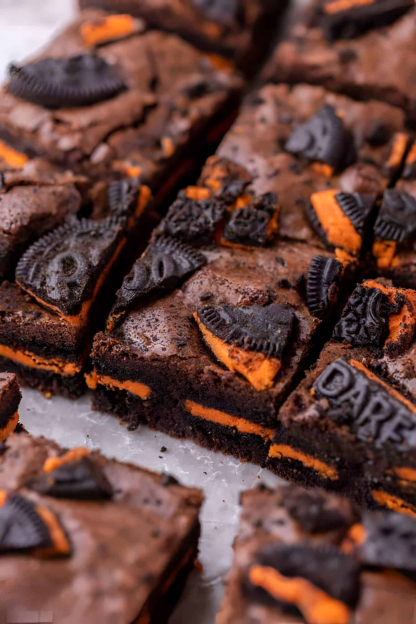 Halloween Oreo brownies cut into squares, topped with broken Halloween Oreos with orange filling.