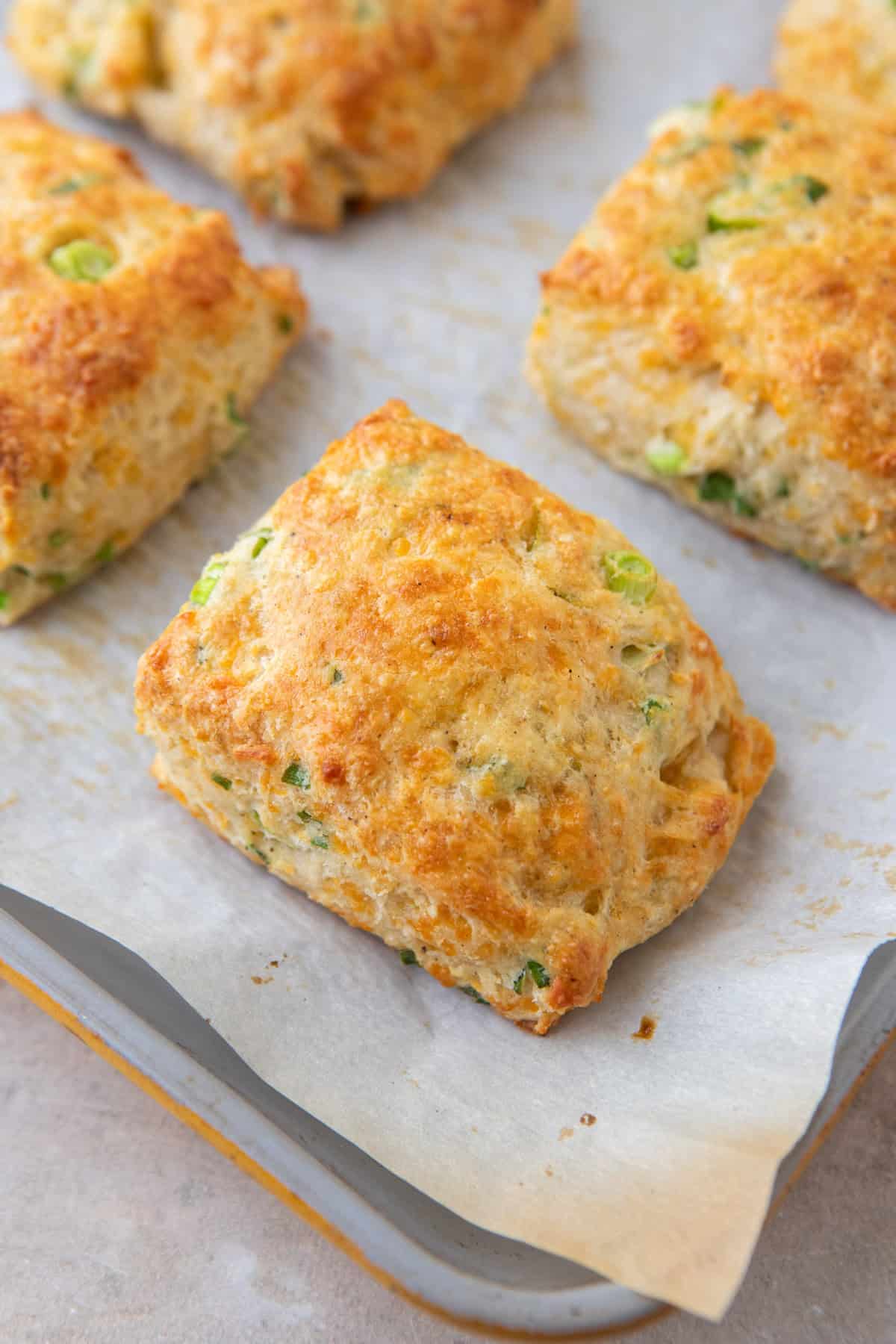 Golden baked cheddar green onion cottage cheese biscuits on a parchment-lined baking sheet.