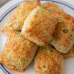 Pile of golden cheddar green onion biscuits on a blue-rimmed plate.