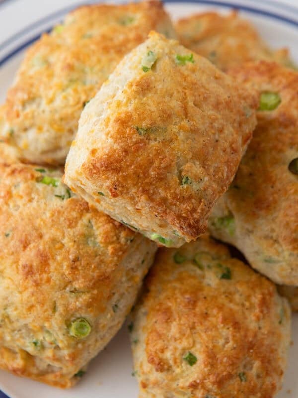 Pile of golden cheddar green onion biscuits on a blue-rimmed plate.