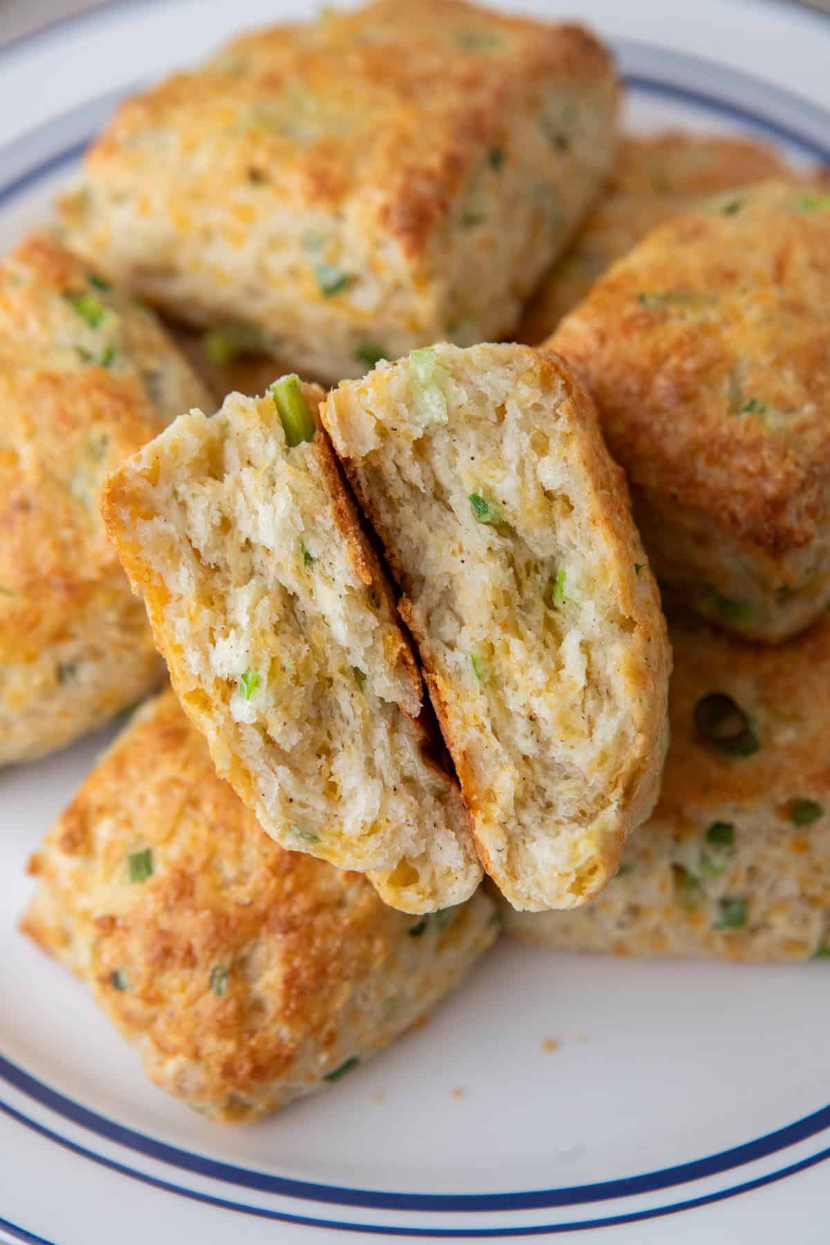 Cheddar green onion cottage cheese biscuit split in half on a plate, showing the flaky layers inside.